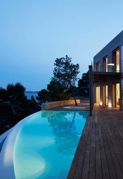 Modern luxury home with illuminated pool at twilight